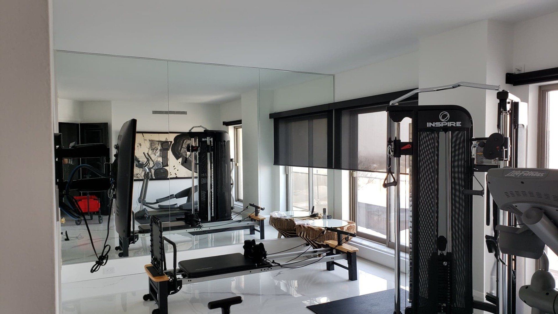 Une salle de sport avec beaucoup d'appareils d'exercice et un grand miroir sur le mur.