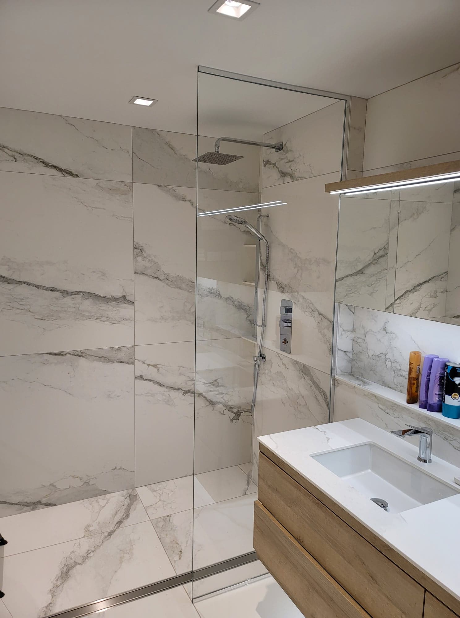 Une salle de bain avec douche à l'italienne, lavabo et miroir.