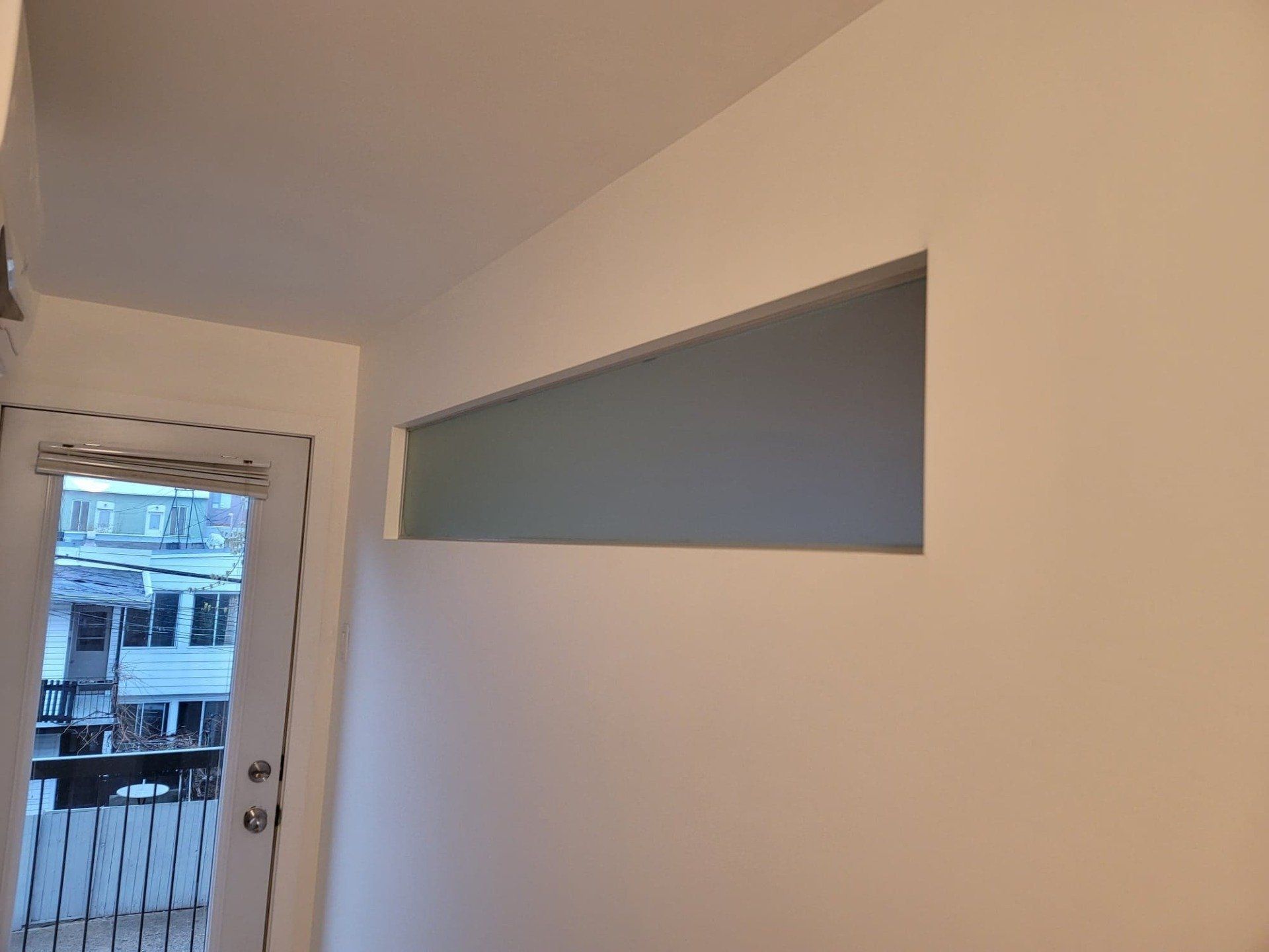 Un mur blanc avec une porte et une fenêtre.