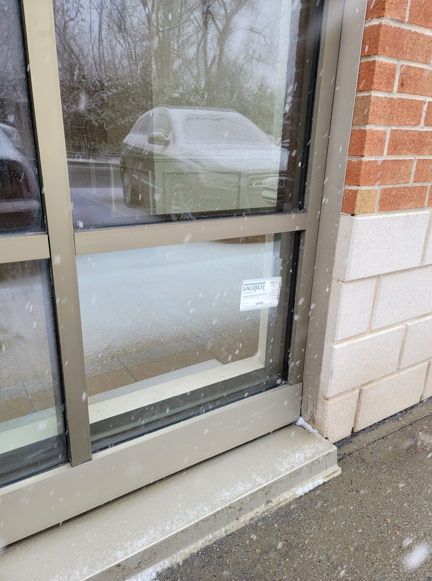 Une voiture se reflète dans la fenêtre d'un immeuble.