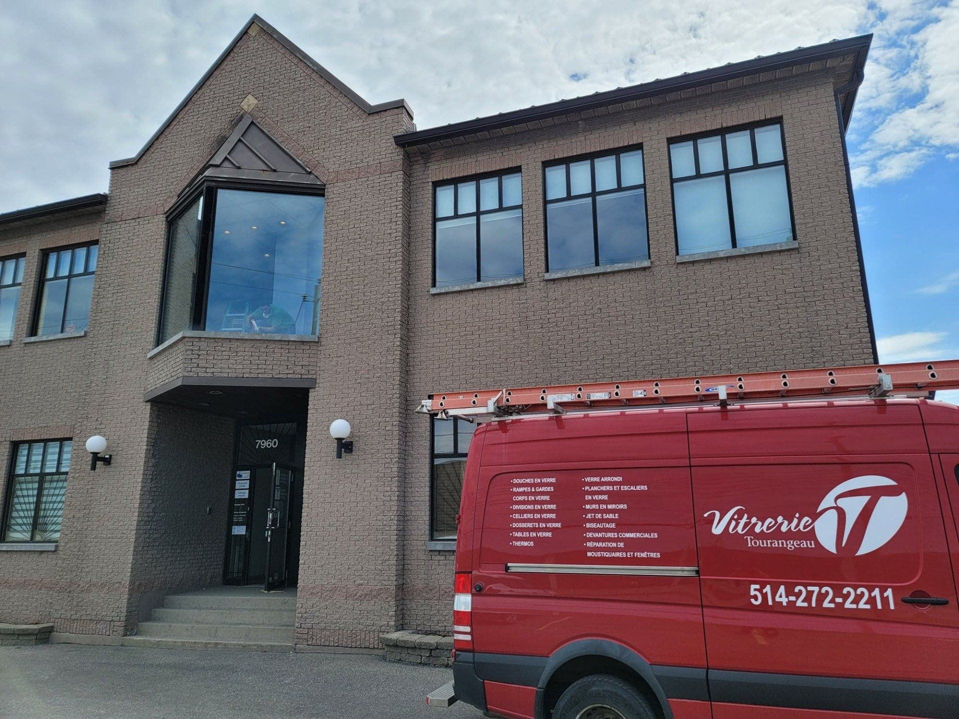 Une camionnette rouge est garée devant un grand bâtiment en briques.