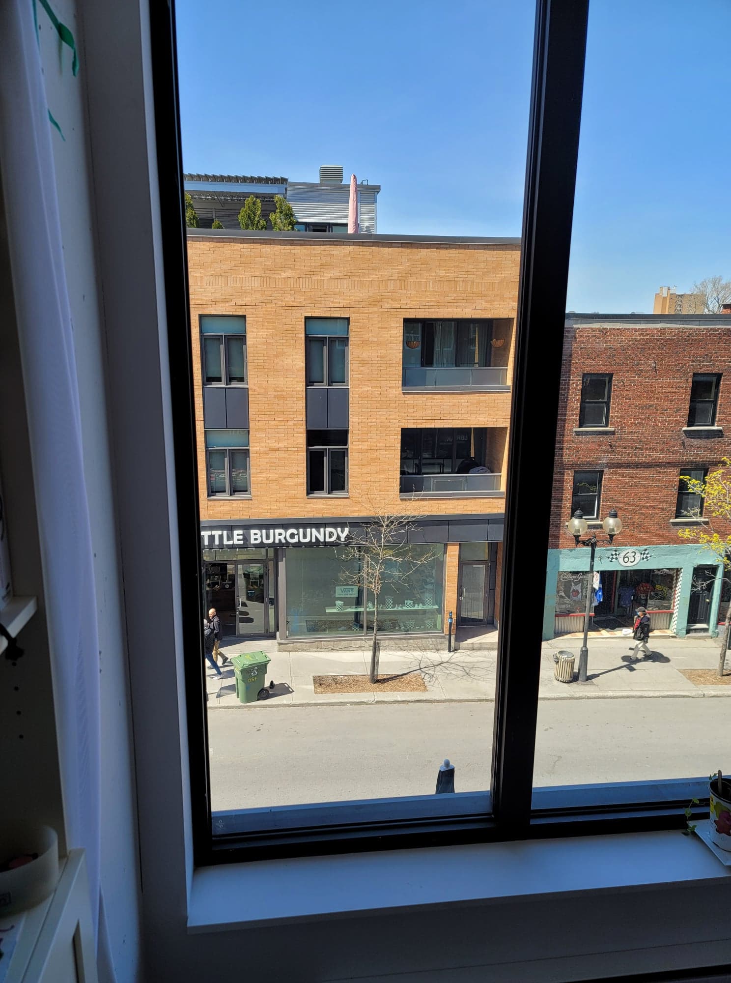 Une vue d'une rue de la ville depuis une fenêtre avec un bâtiment en briques en arrière-plan.