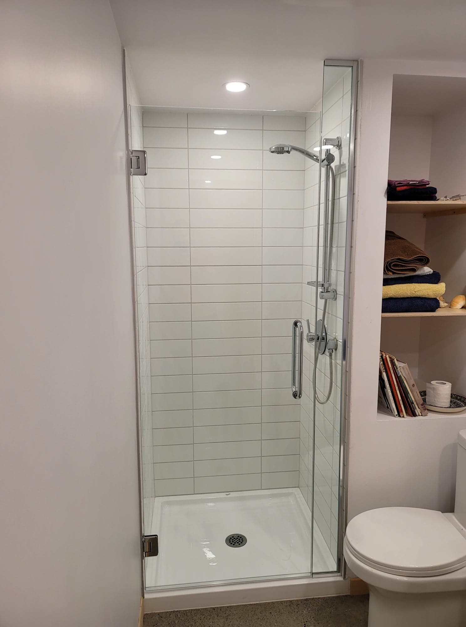 Une salle de bain avec WC et une cabine de douche avec porte vitrée.