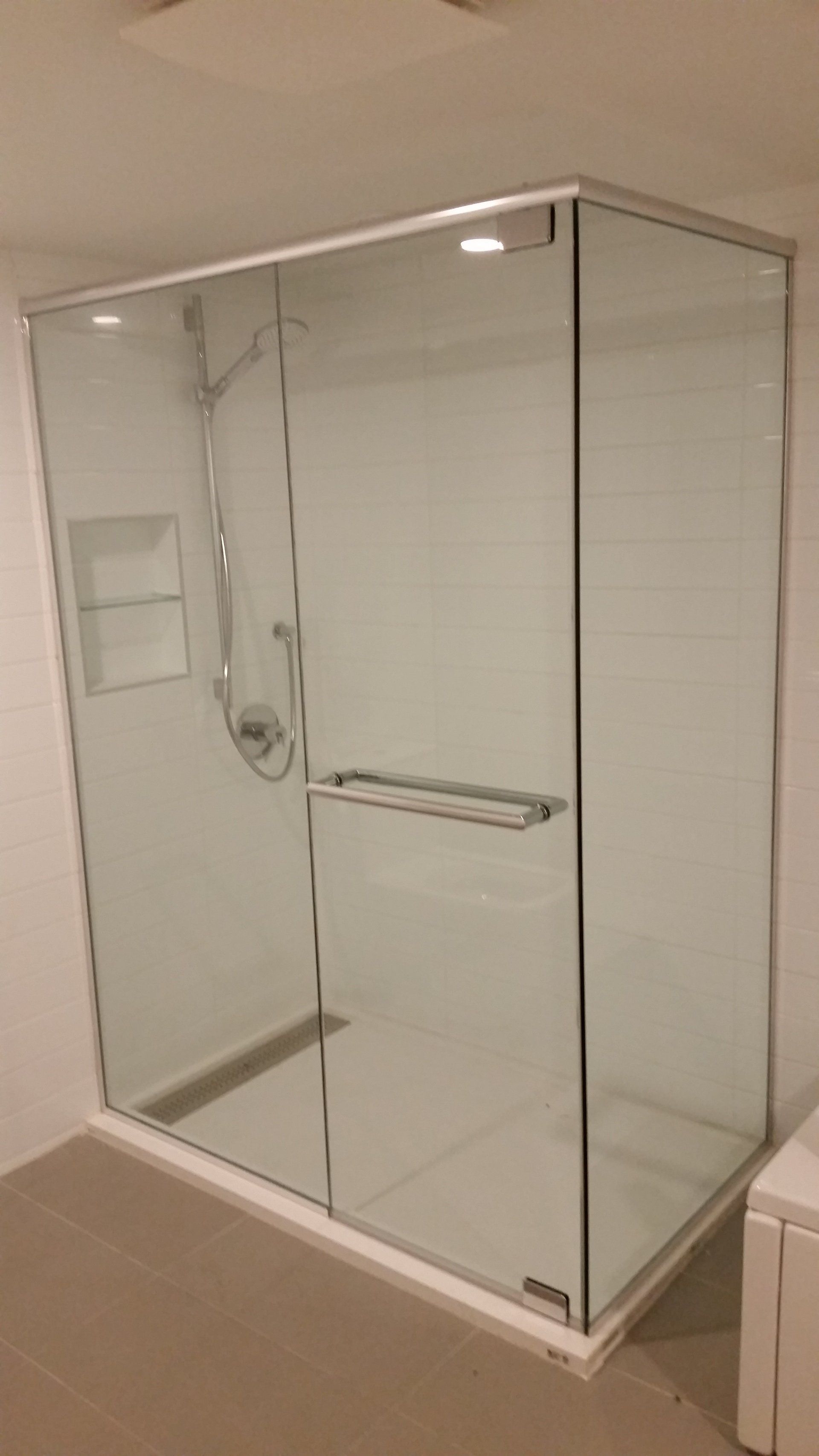 Une cabine de douche avec une porte vitrée et une pomme de douche dans une salle de bain.