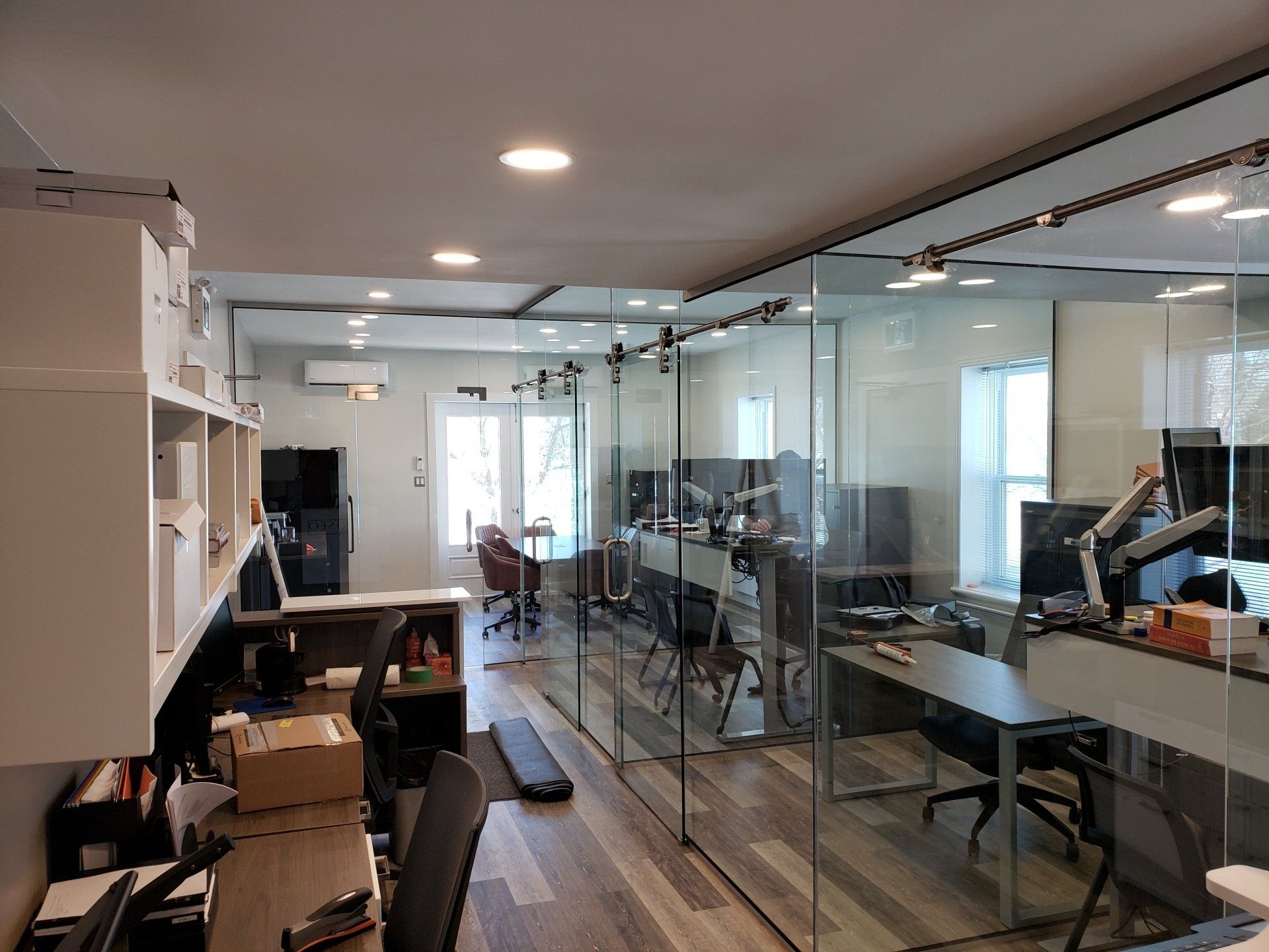 Un grand bureau avec beaucoup de bureaux et de chaises et des portes coulissantes en verre.