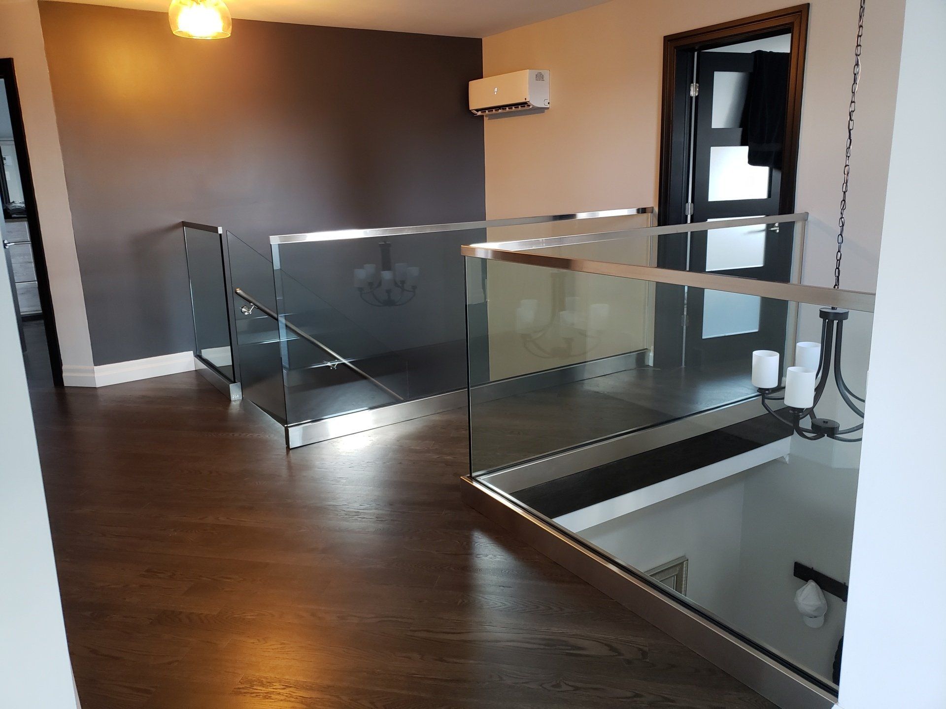 Un couloir avec une rampe en verre menant à un escalier.