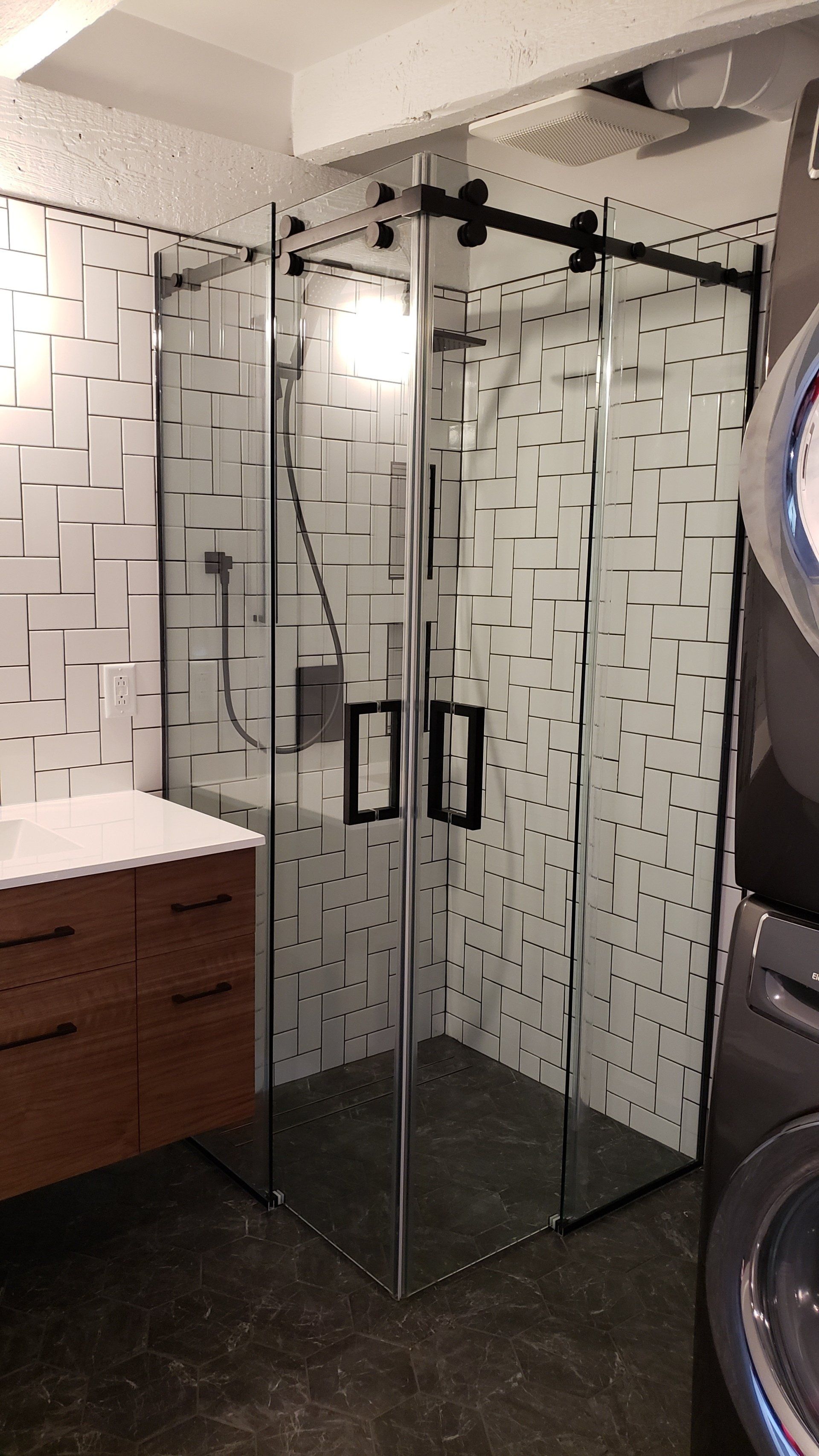 Une salle de bain avec une porte de douche coulissante en verre et un lavabo.