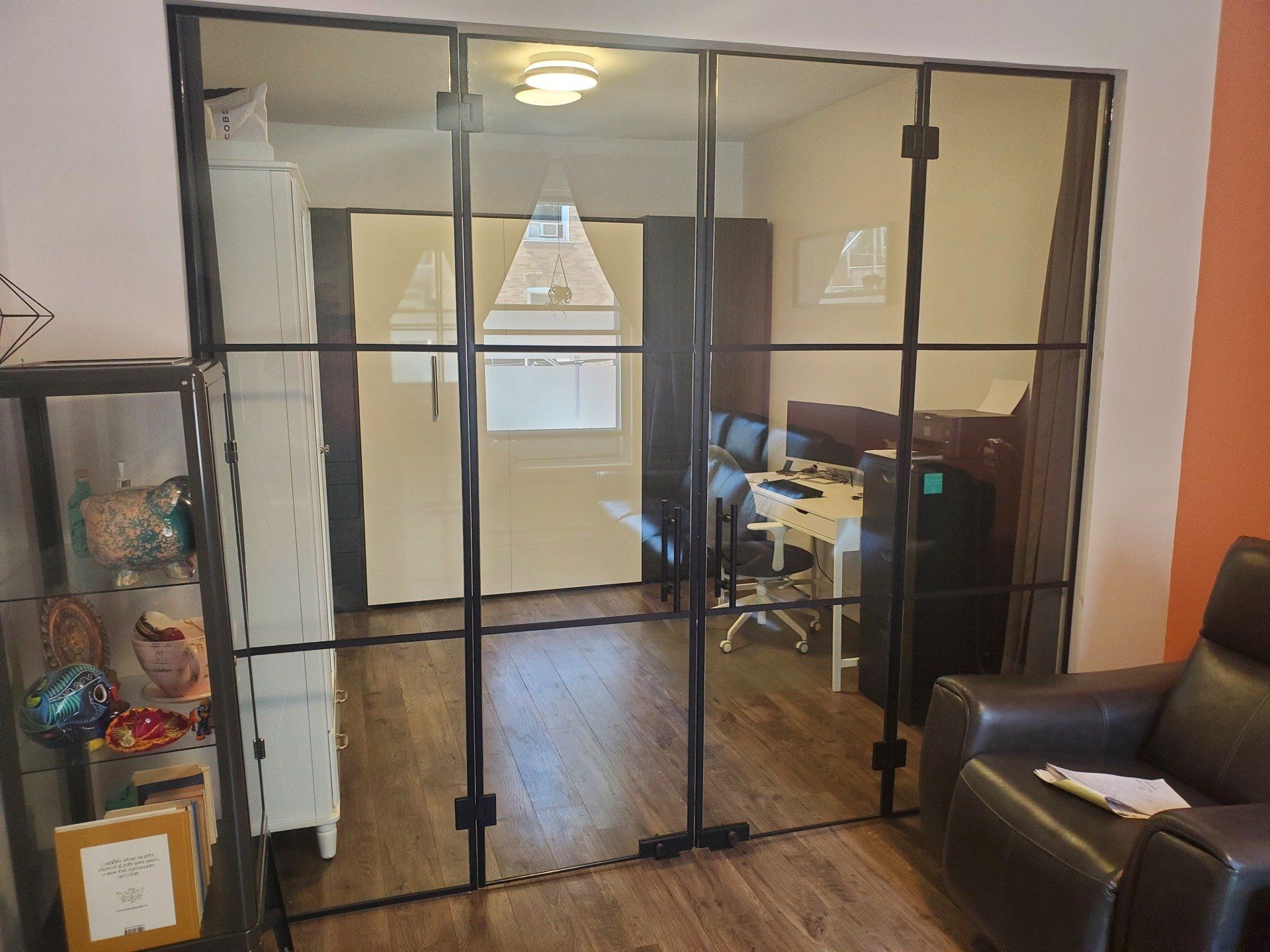 Un salon avec une chaise, un bureau et des portes coulissantes en verre.