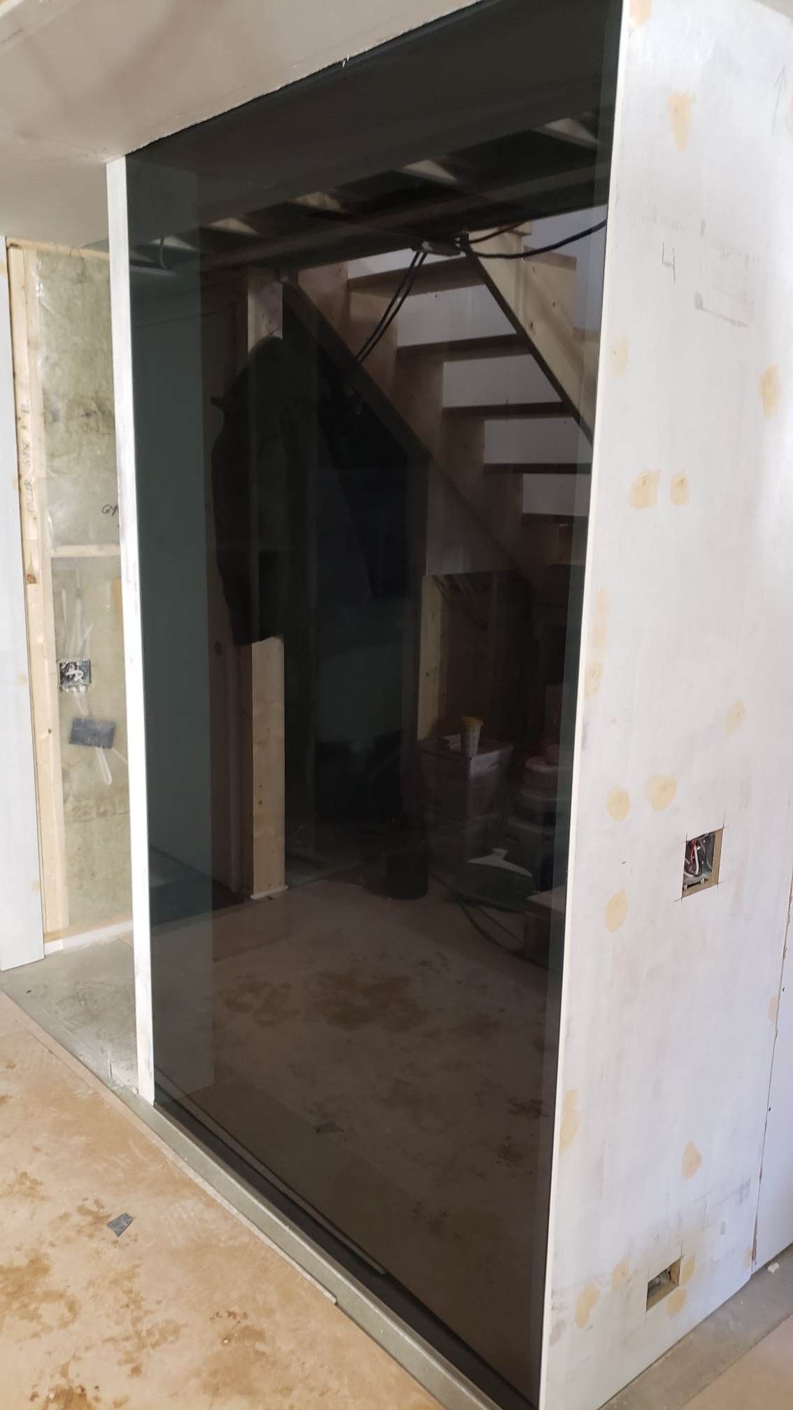 Une pièce avec un escalier derrière un mur de verre.