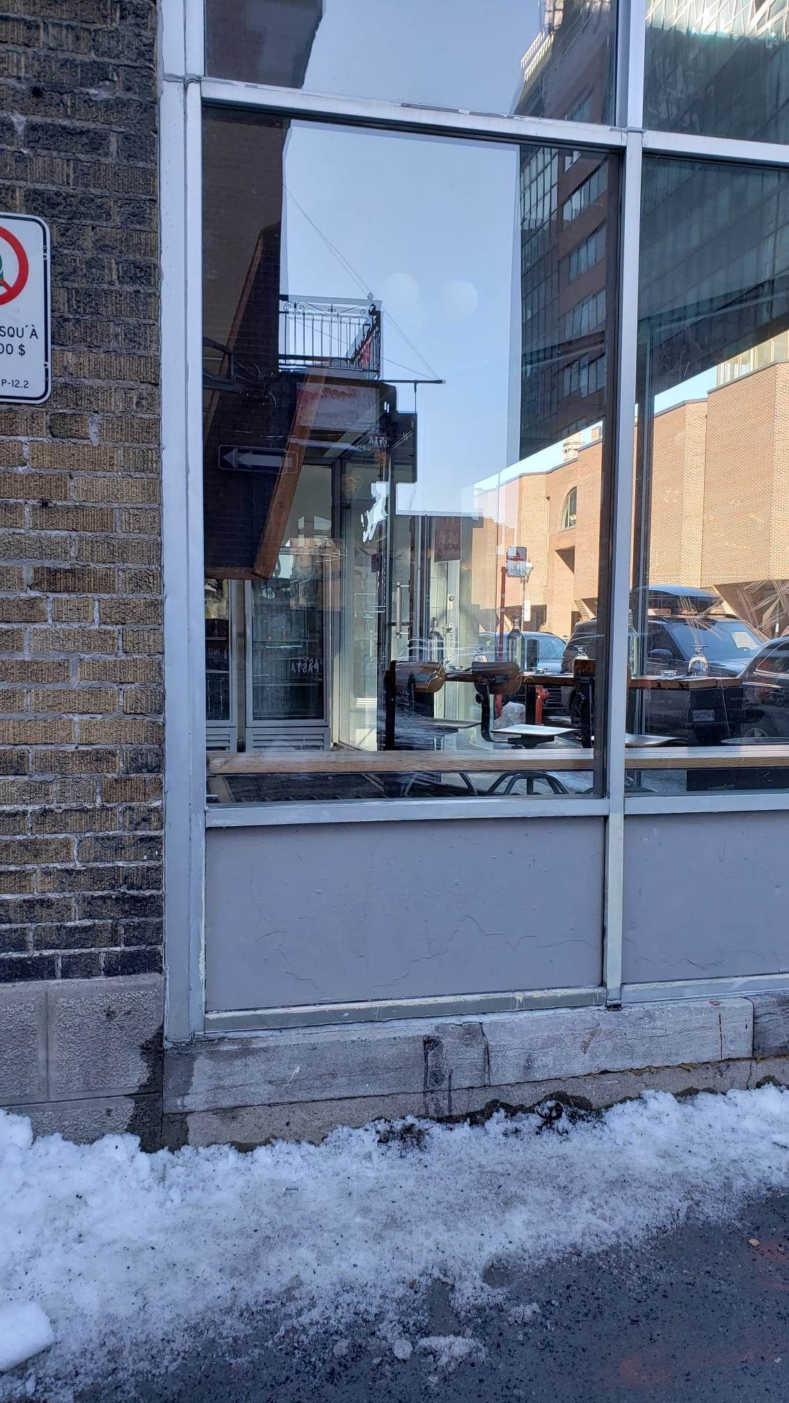 Un bâtiment en briques avec une grande fenêtre et un panneau indiquant qu'il est interdit de stationner.