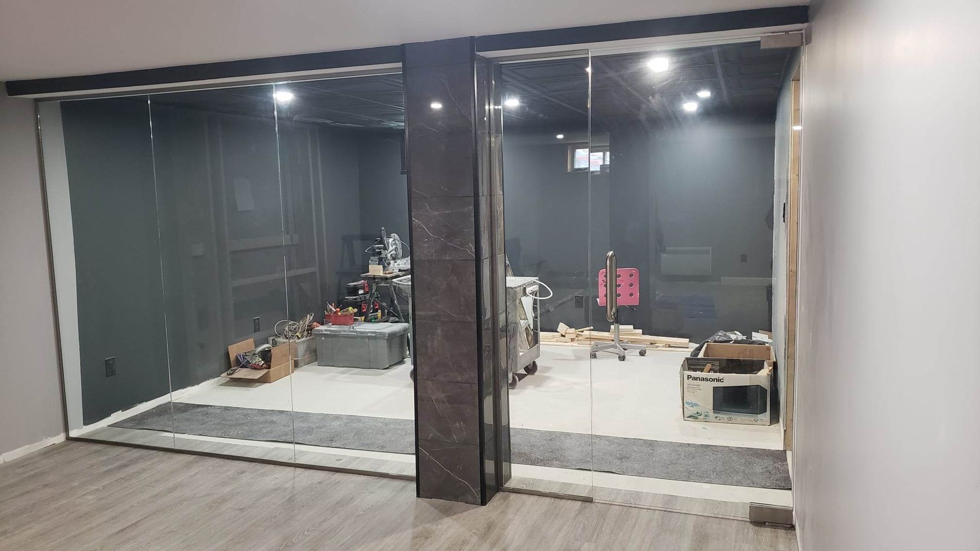 Une pièce avec beaucoup de portes vitrées et un plancher en bois.