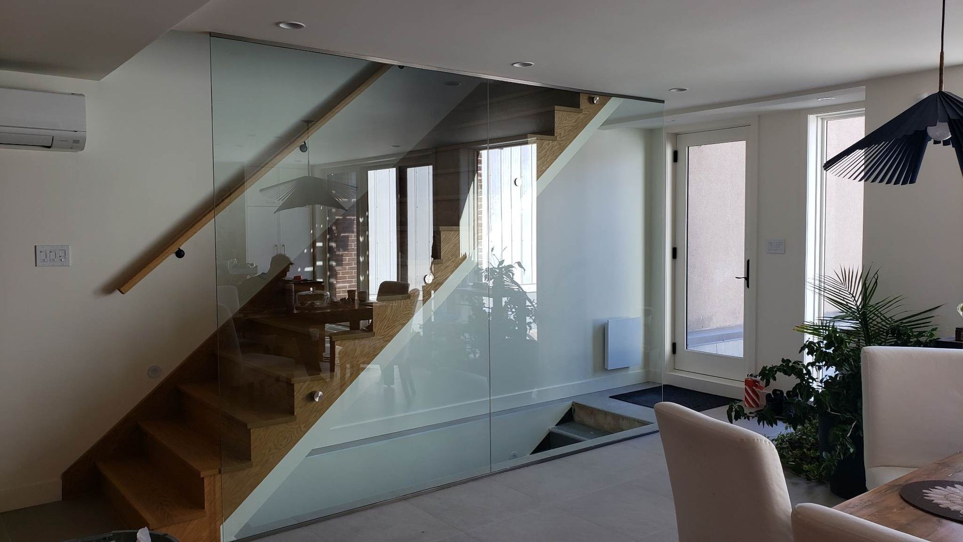 Un escalier en bois avec une rampe en verre dans un salon.