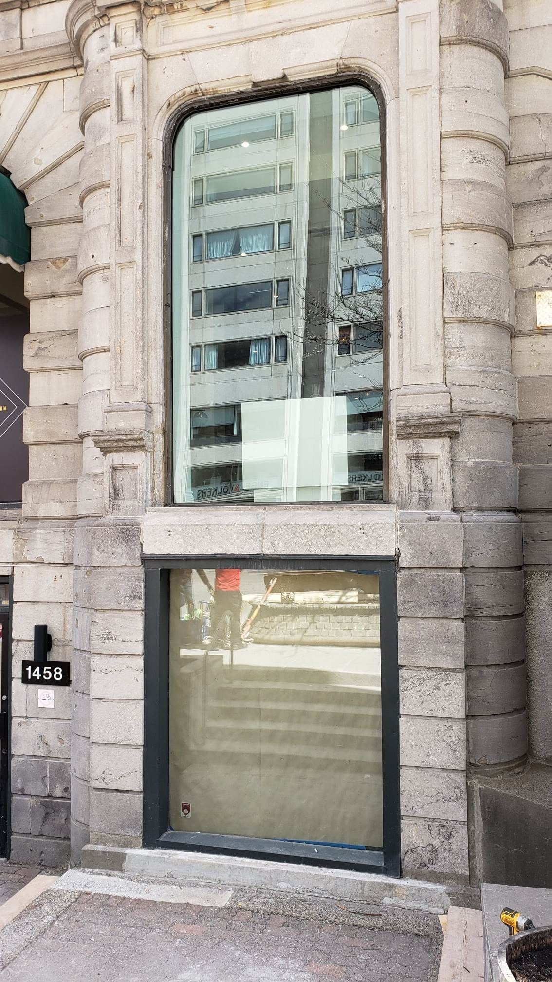 Un bâtiment avec une grande fenêtre et un reflet d'un bâtiment dans la fenêtre.