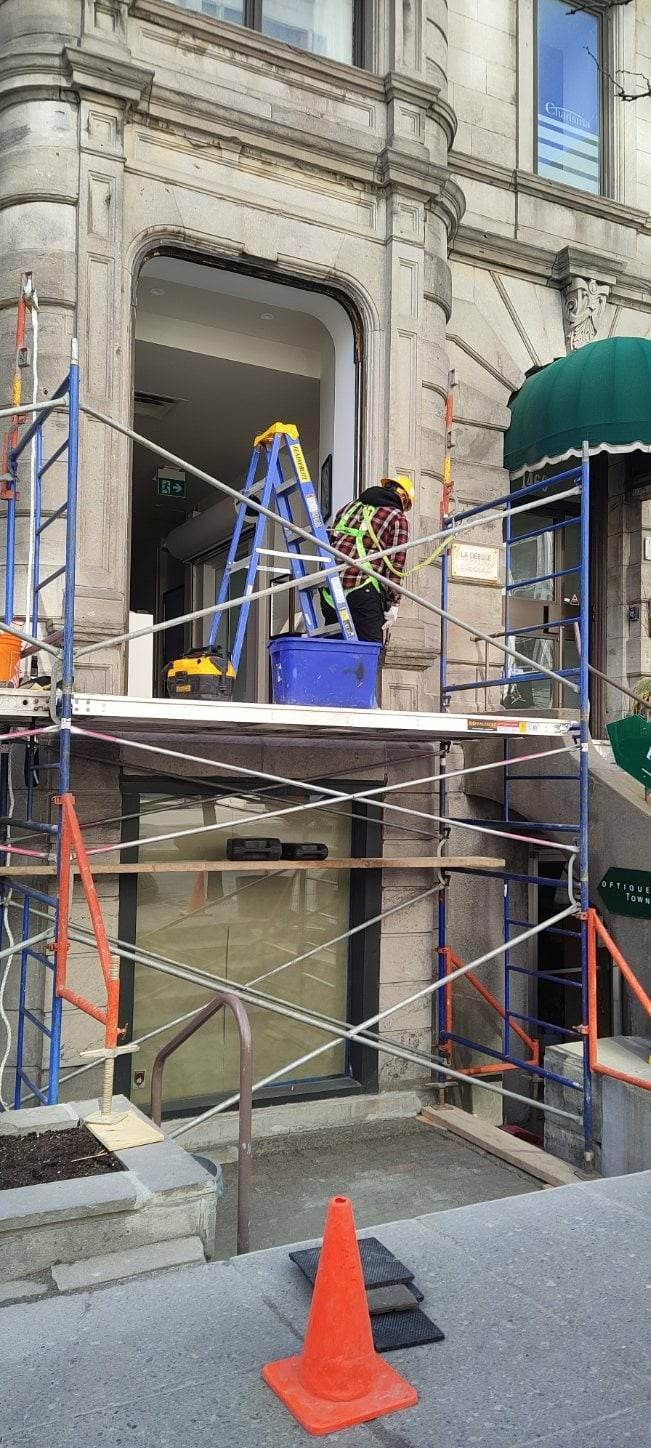 Un homme se tient debout sur un échafaudage devant un bâtiment.