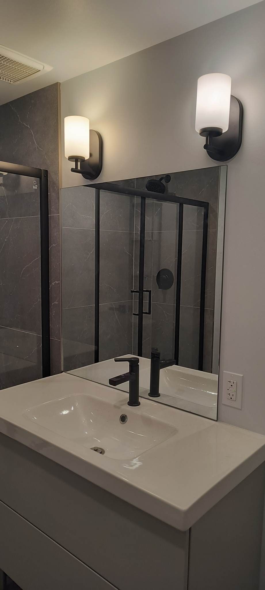 Une salle de bain avec lavabo, miroir et cabine de douche.