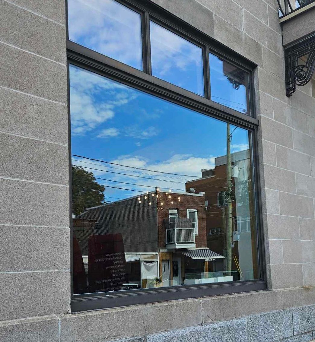 Une grande fenêtre avec le reflet d'une maison à l'intérieur