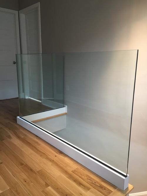 Un escalier avec une rampe en verre et un plancher en bois.