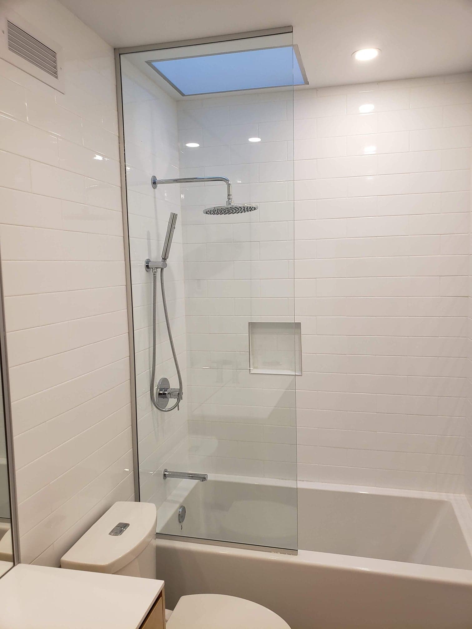 Une salle de bain avec baignoire, WC, douche et puits de lumière.