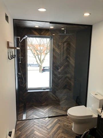 Une salle de bain avec douche à l'italienne, WC et fenêtre.