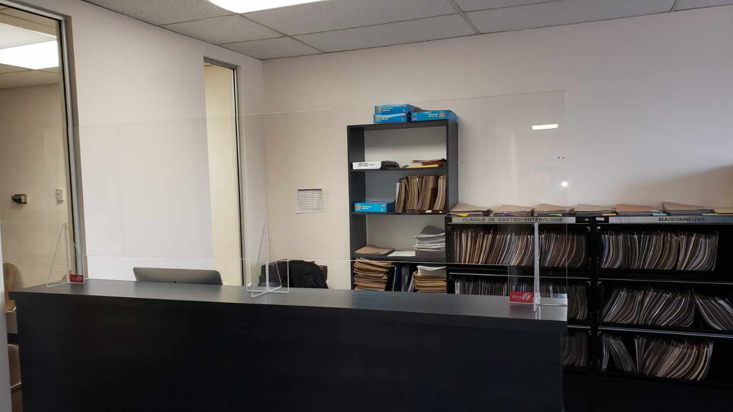 Une pièce avec un bureau, des étagères et une cloison en verre.