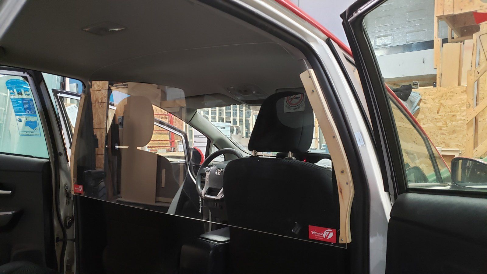 L'intérieur d'une voiture avec une barrière en plastique transparent entre les sièges.