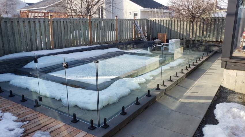 Une piscine entourée de neige et d'une clôture