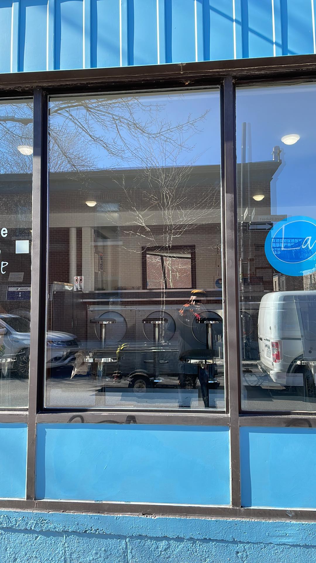 Un bâtiment bleu avec une grande fenêtre et une camionnette garée devant.