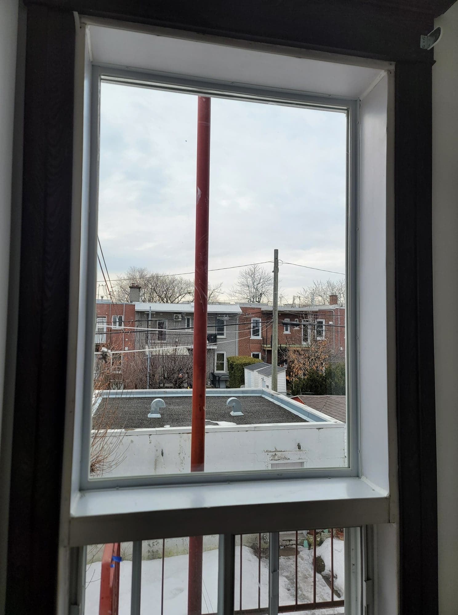 Une fenêtre avec vue sur le toit d'un immeuble.