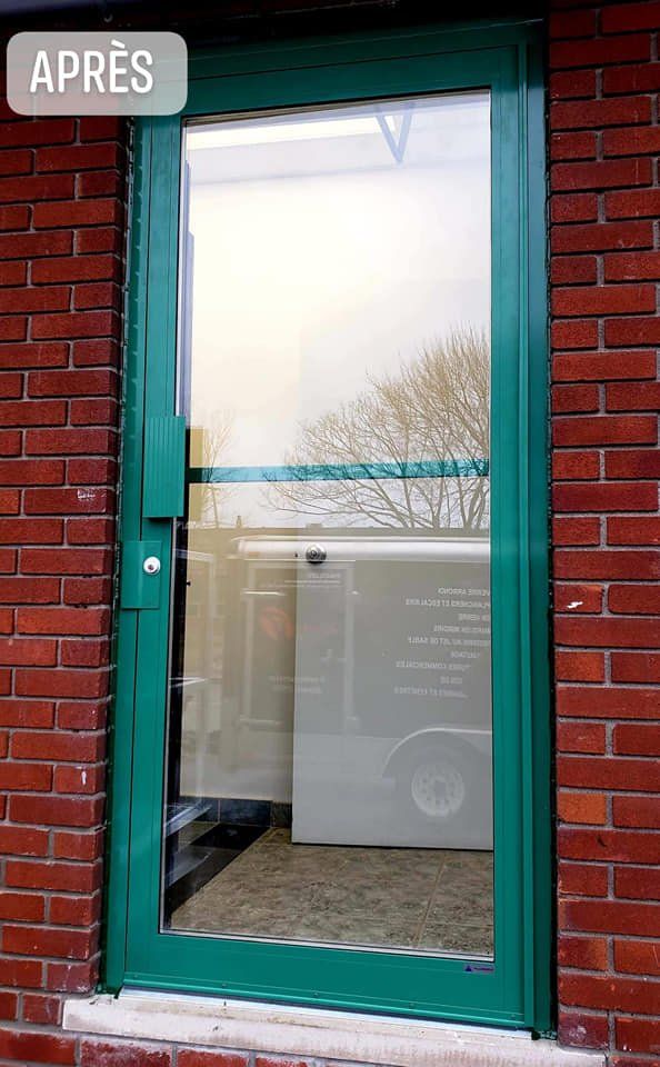 A green door is sitting on a brick wall.