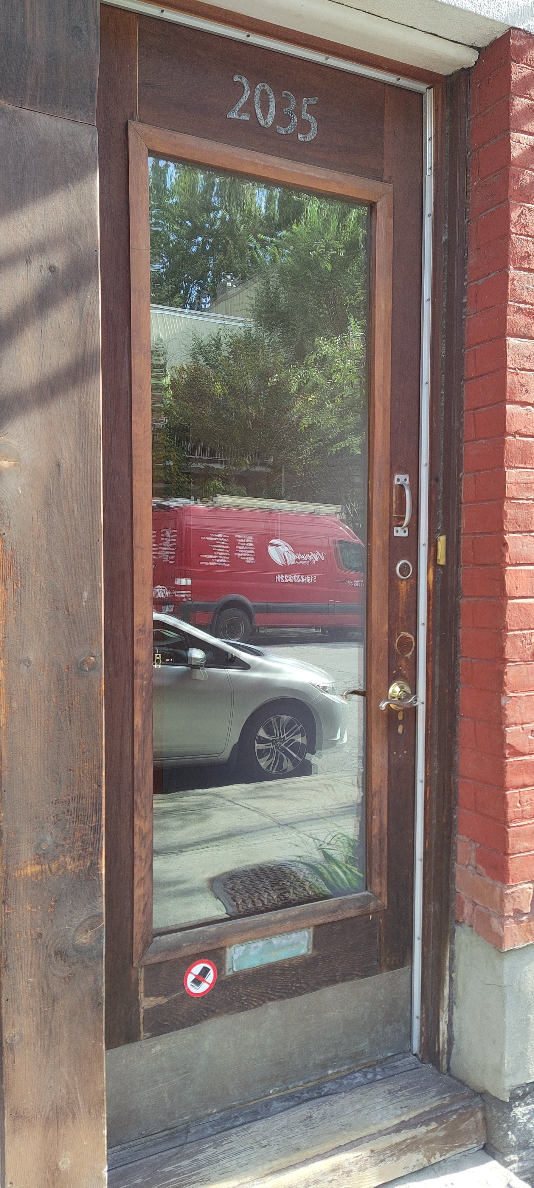 A door with a reflection of a red van in it.