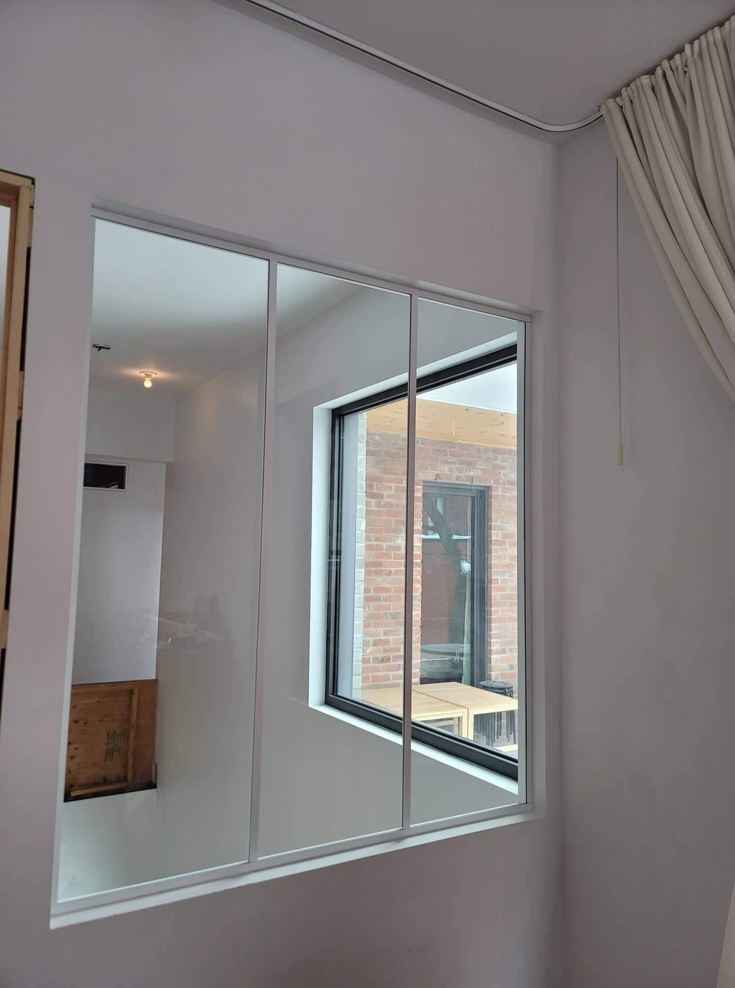 Une pièce avec une grande fenêtre et un miroir sur le mur