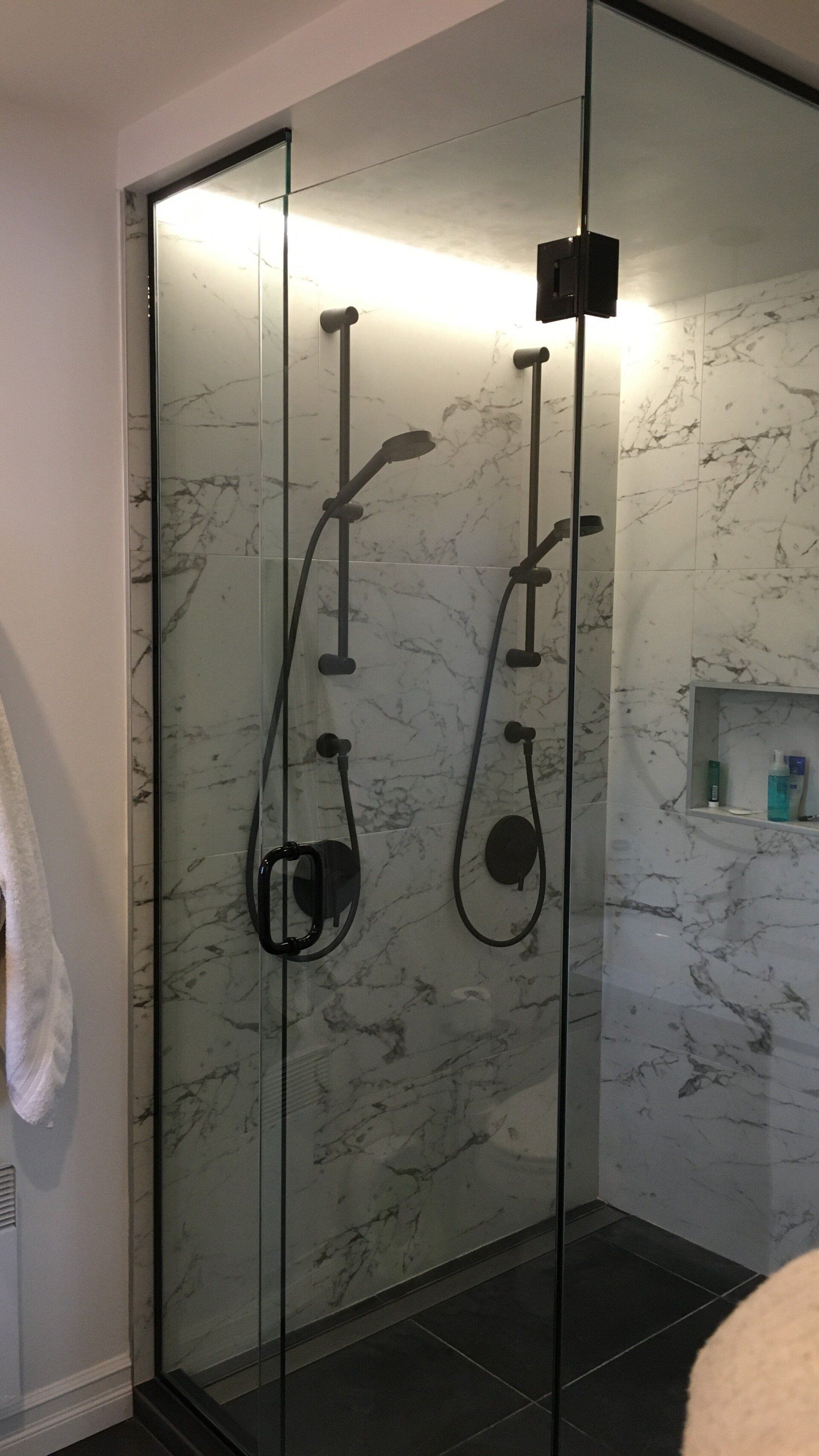 Une salle de bain avec douche à l'italienne avec deux pommeaux de douche.