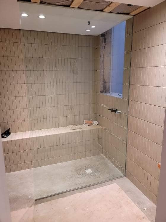 Une salle de bain avec douche à l'italienne et fenêtre.