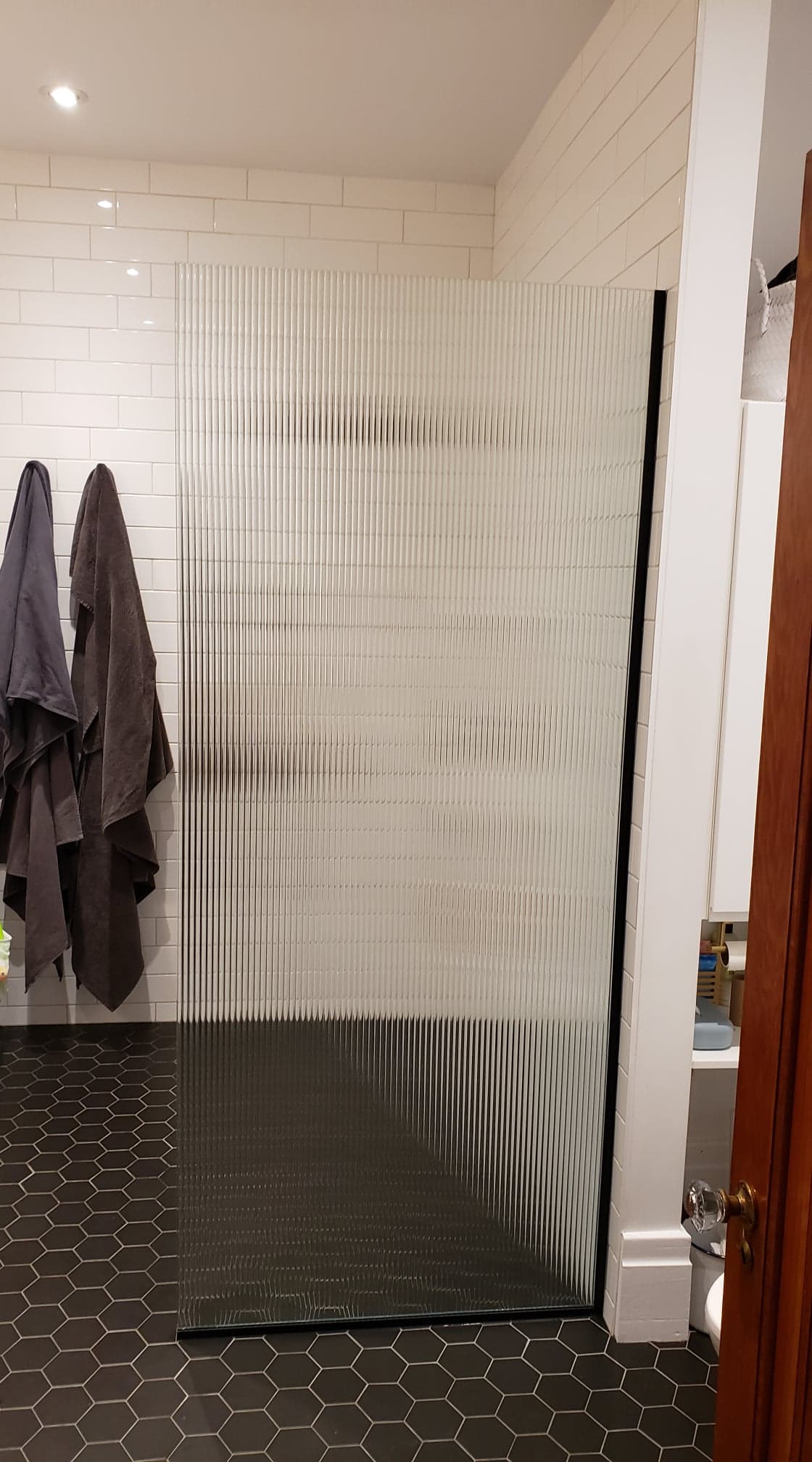 Une salle de bain avec une douche à l'italienne et un grand miroir.