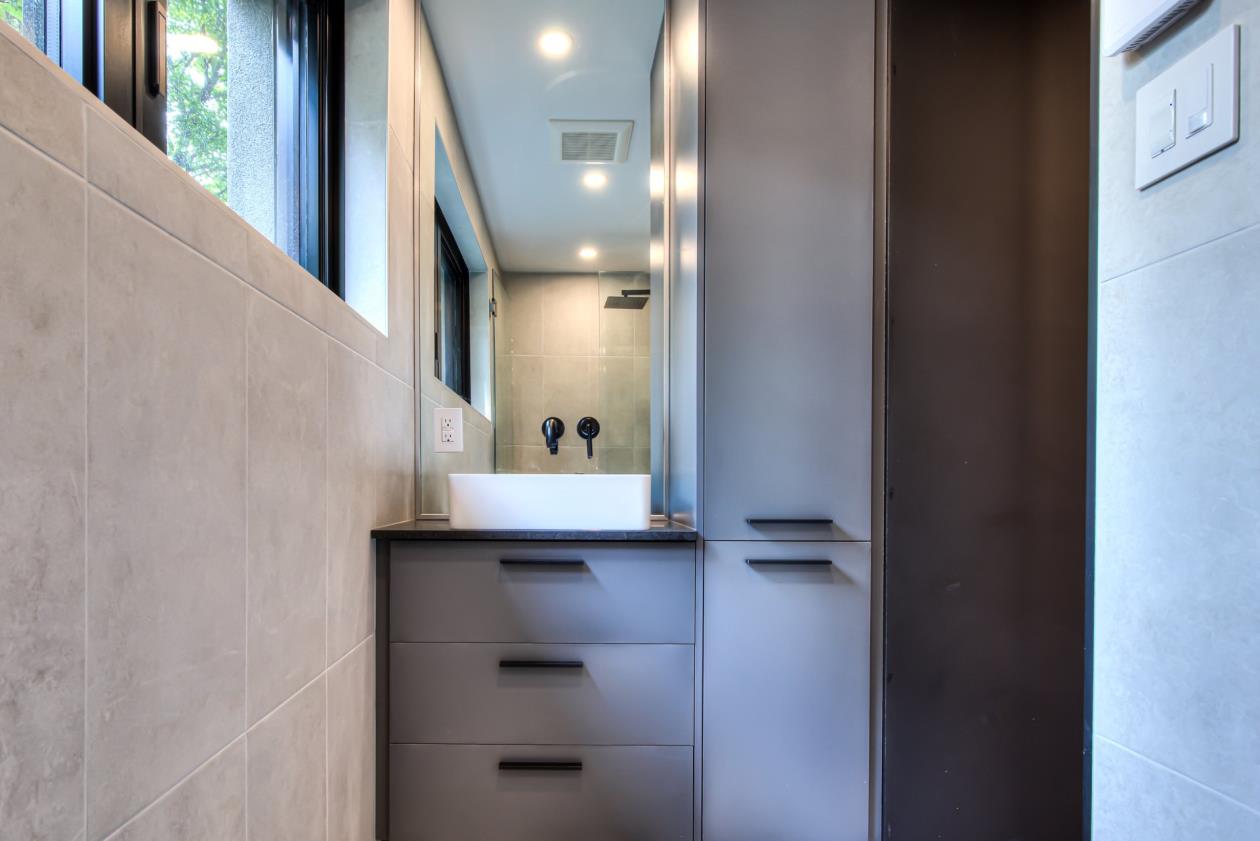 Une salle de bain avec un lavabo, des armoires et une fenêtre.