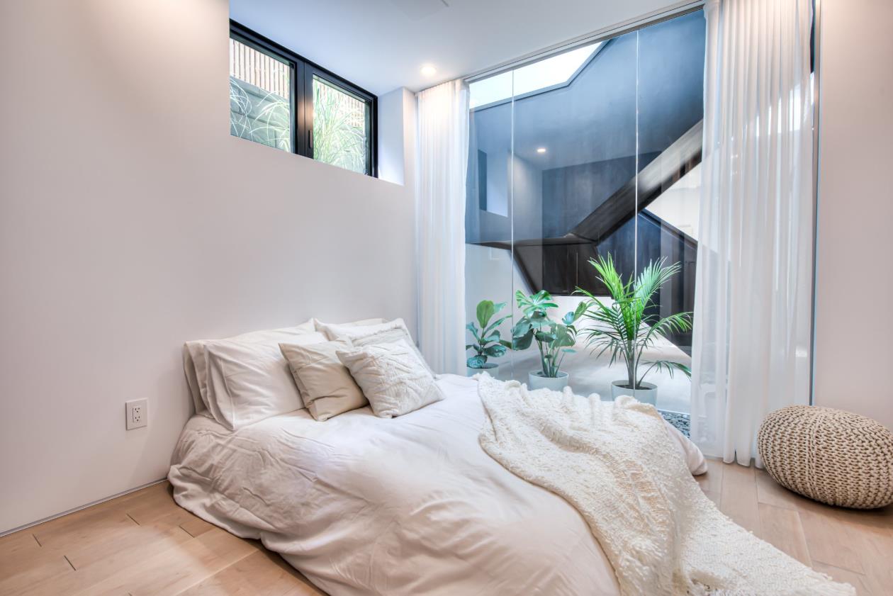 Une chambre avec un lit et une fenêtre avec vue sur une cour.