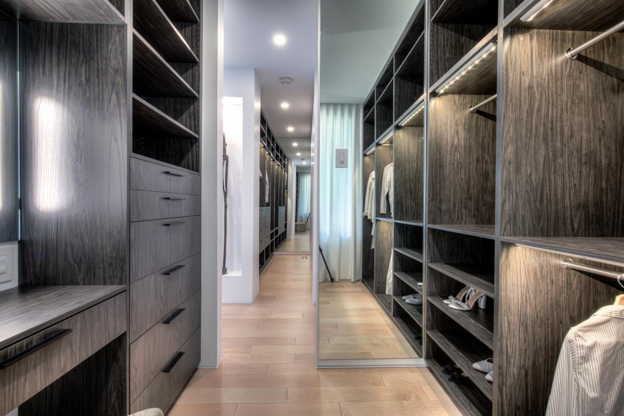 Un dressing avec beaucoup d'étagères et un miroir.