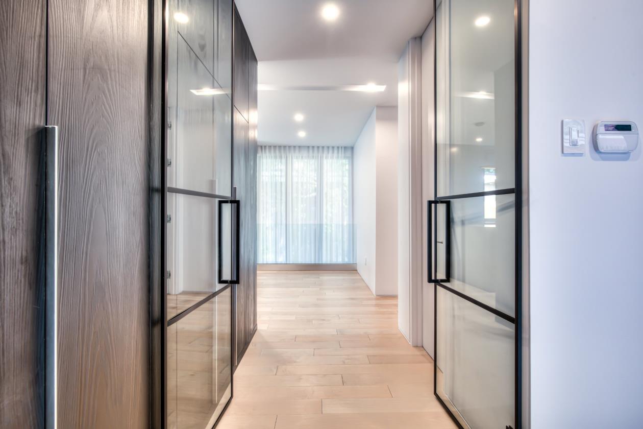 Un couloir avec des portes vitrées et des murs en bois dans une maison.