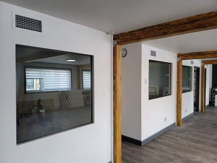 Une pièce avec beaucoup de fenêtres et des poutres en bois.