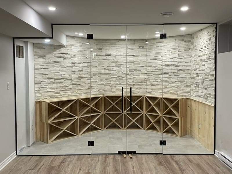 Une cave à vin avec une paroi vitrée et des étagères en bois.