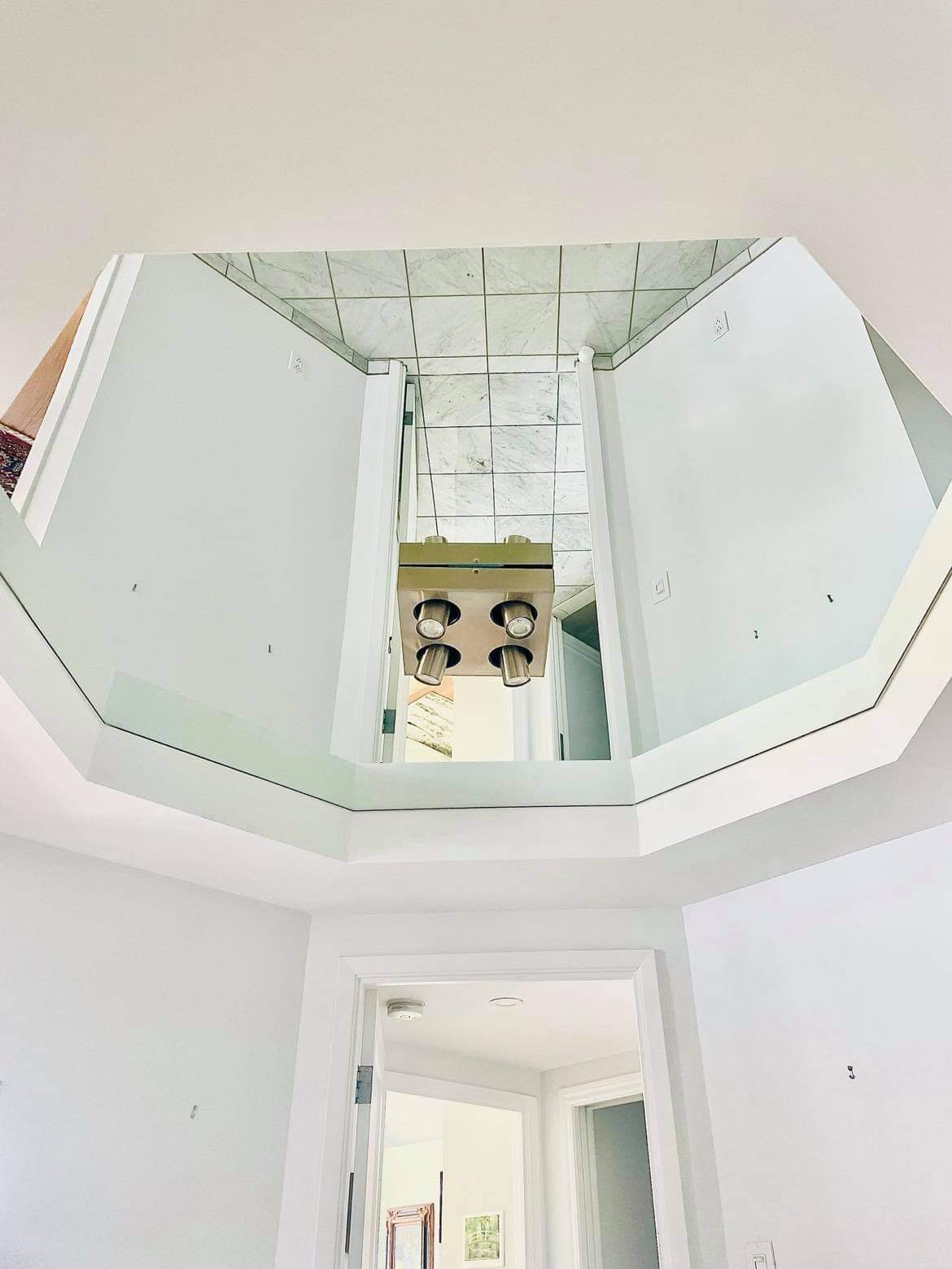 Une pièce avec un plafond en miroir et le reflet d'un poêle dans le miroir.