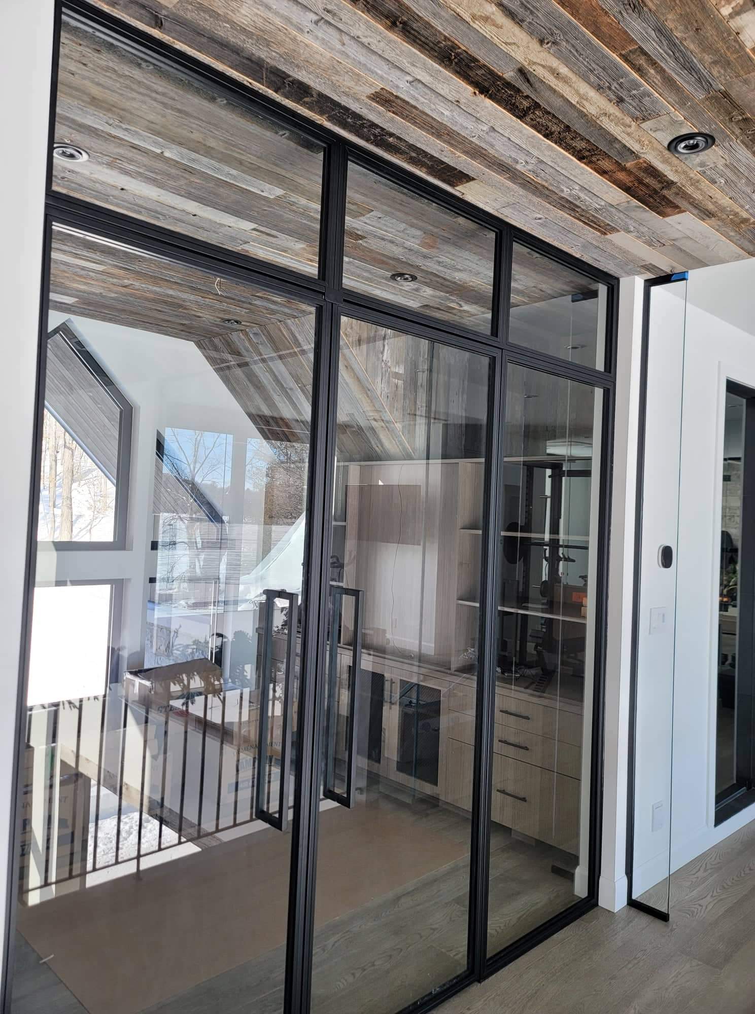 Une pièce avec beaucoup de portes vitrées et un plafond en bois.