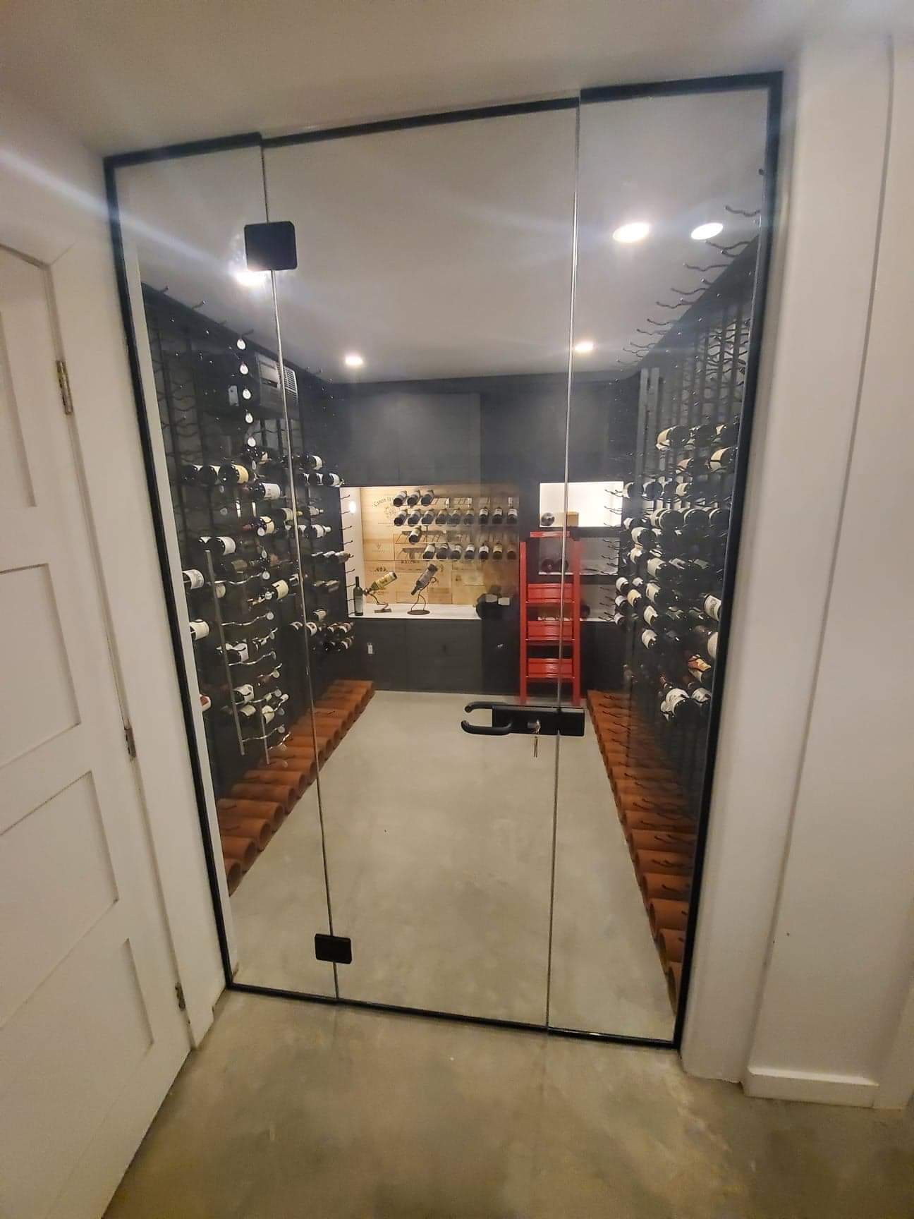 Une cave à vin avec une porte vitrée et beaucoup de bouteilles de vin.