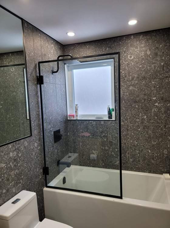 Une salle de bain avec baignoire, WC, miroir et cabine de douche.