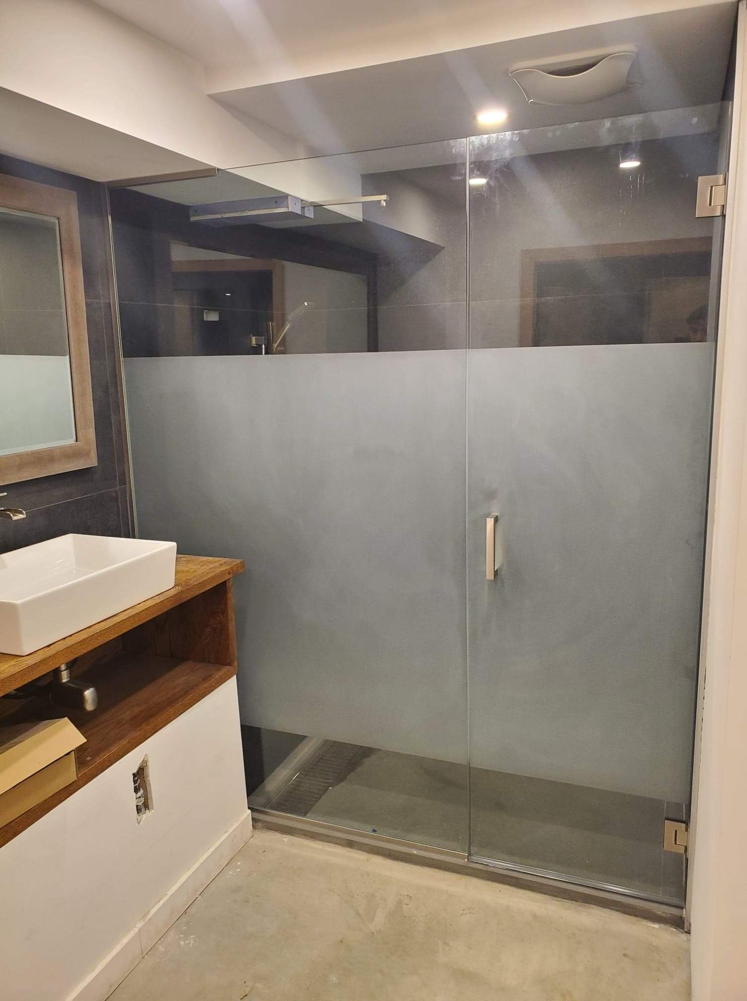 Une salle de bain avec lavabo, miroir et cabine de douche.