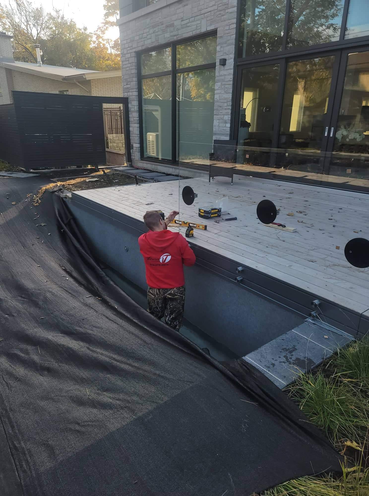 Un homme portant un sweat à capuche rouge travaille sur une piscine.