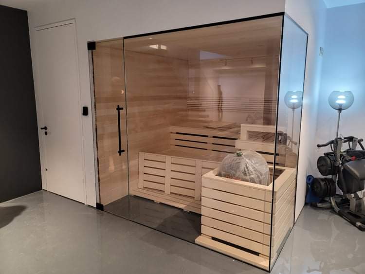 Un sauna en bois avec une porte vitrée dans une pièce.