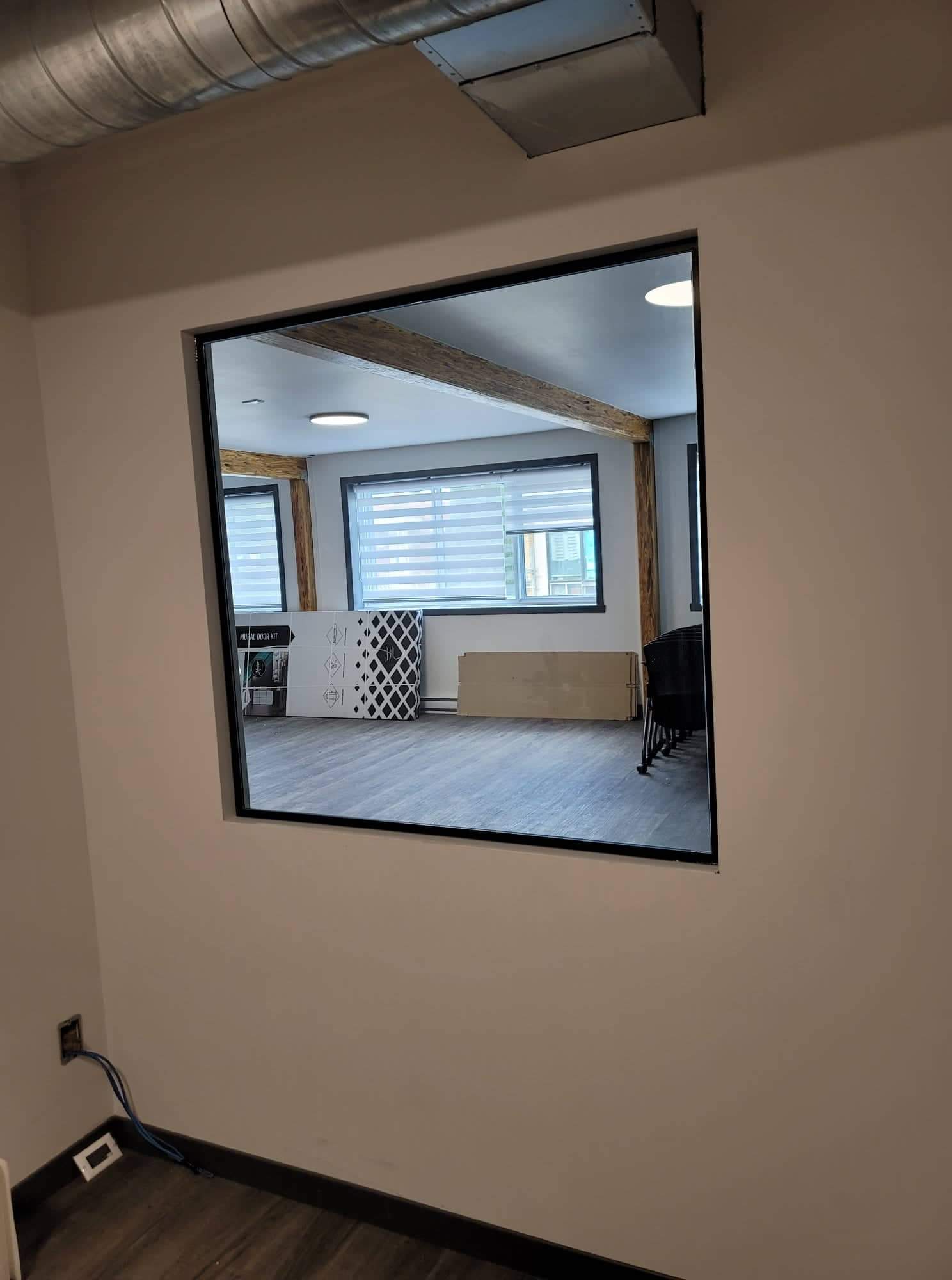 Il y a une fenêtre dans le mur qui donne sur une pièce.