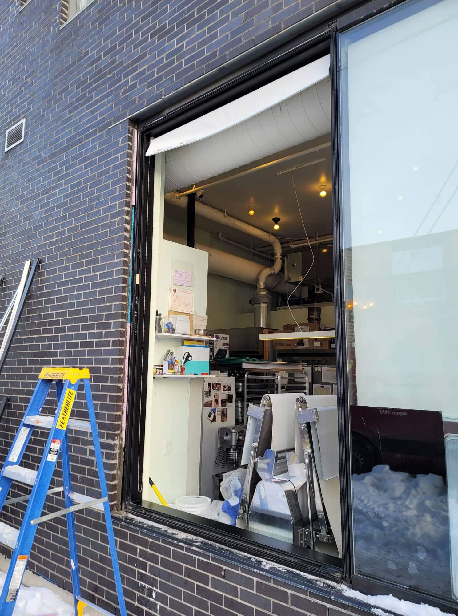 Une échelle est posée sur le côté d'un bâtiment à côté d'une fenêtre.