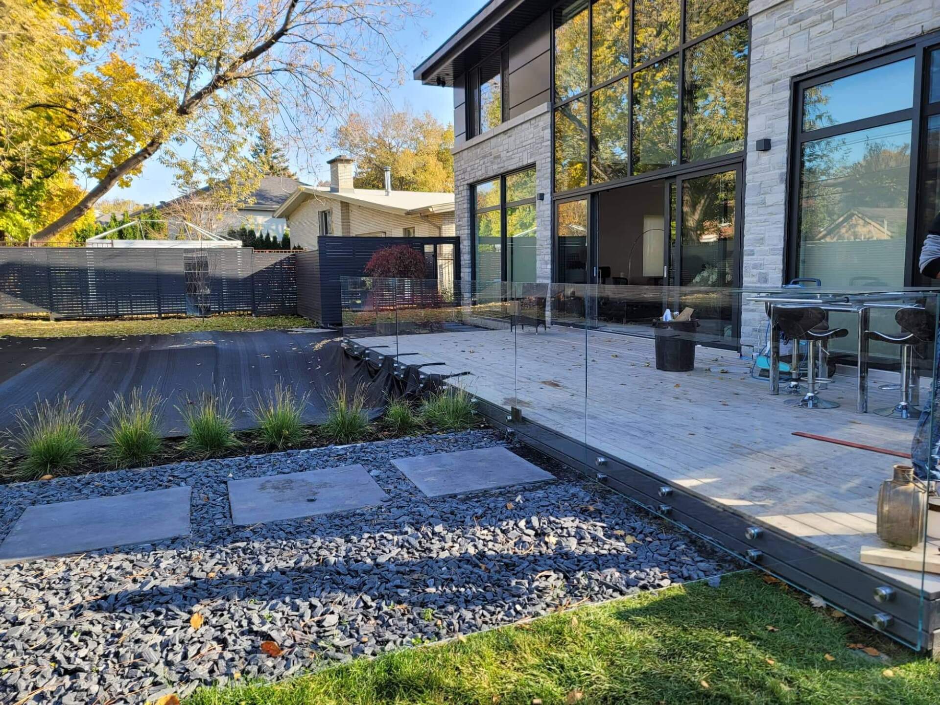 Une grande maison avec un patio et une clôture devant.